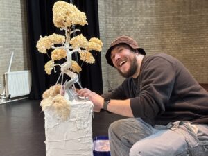 Kunstenaar Damiën aan het werk met zijn boomsculptuur